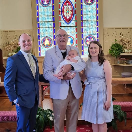 Dr. Hayes holding a newly baptized infant with the family at Christ Anglican Church